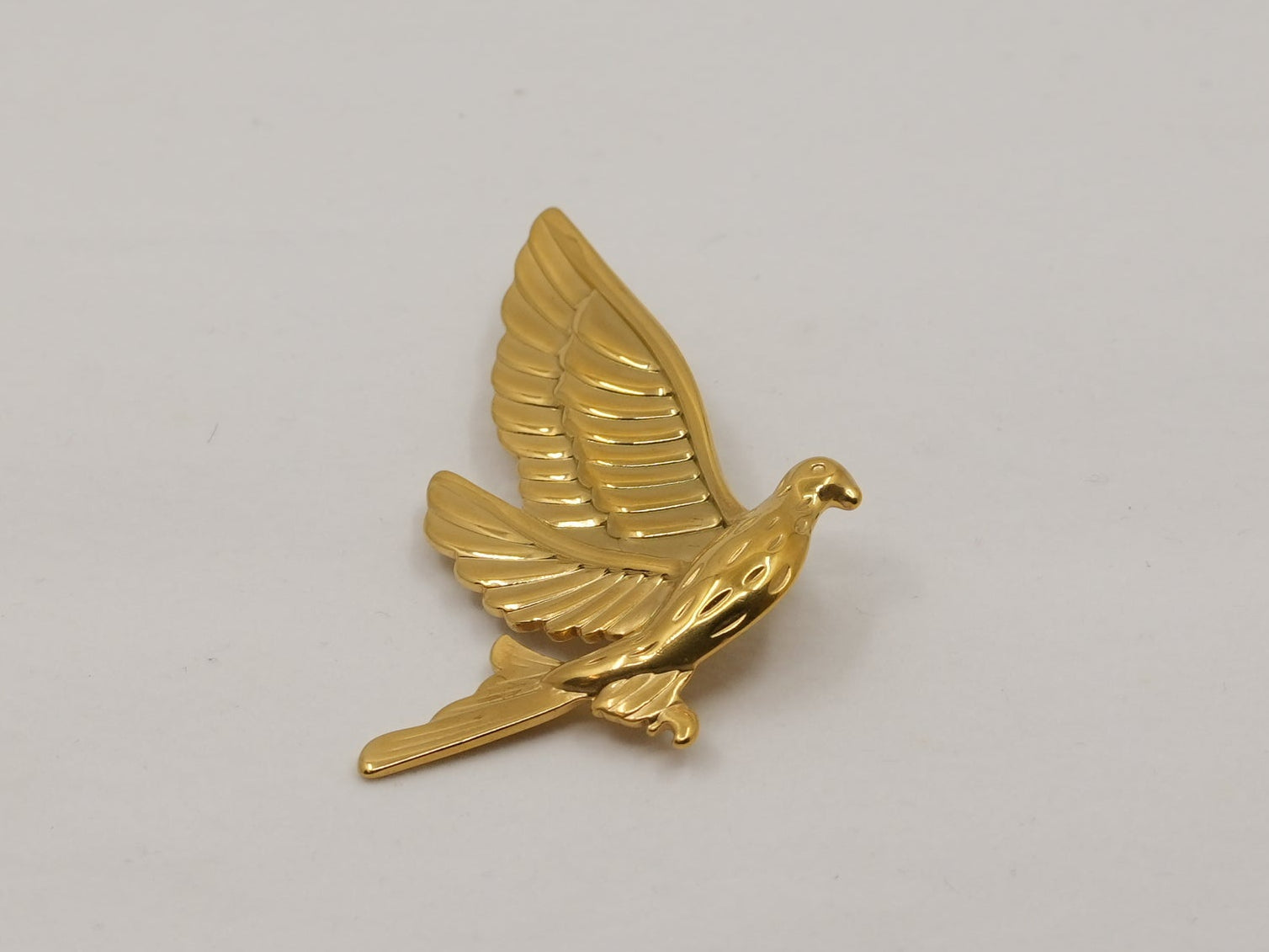 Gold dove-shaped object on a gray background