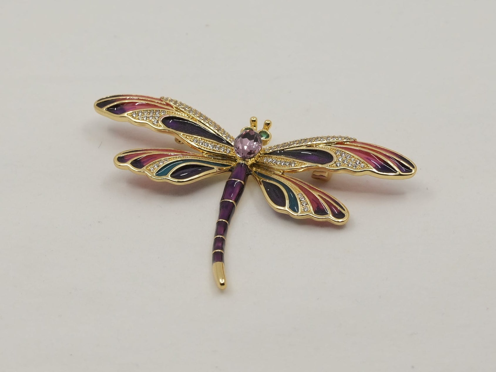 Decorative dragonfly brooch on a light gray background