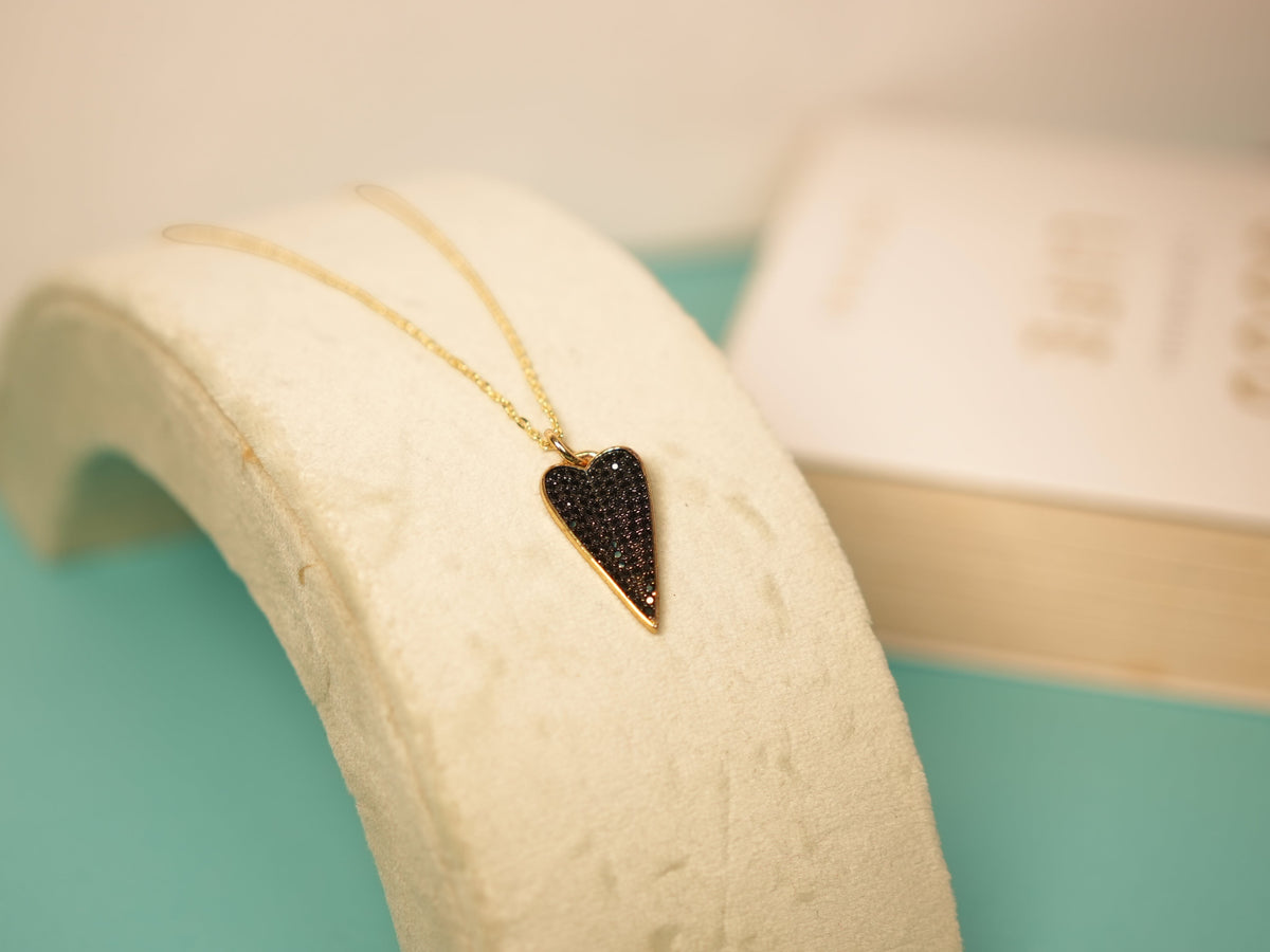 Daga-accessories Heart of eclipse black necklace featuring a gold chain and a black stone heart pendant.