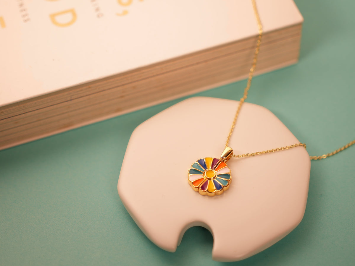 Daga-accessories Bloom Aura Necklace featuring a gold chain and a vibrant, multi-colored enamel floral pendant.