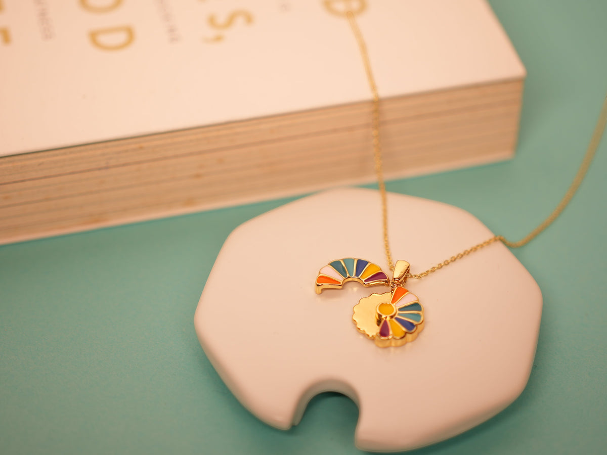 Daga-accessories Bloom Aura Necklace featuring gold-tone floral charms with vibrant multi-colored enamel accents.