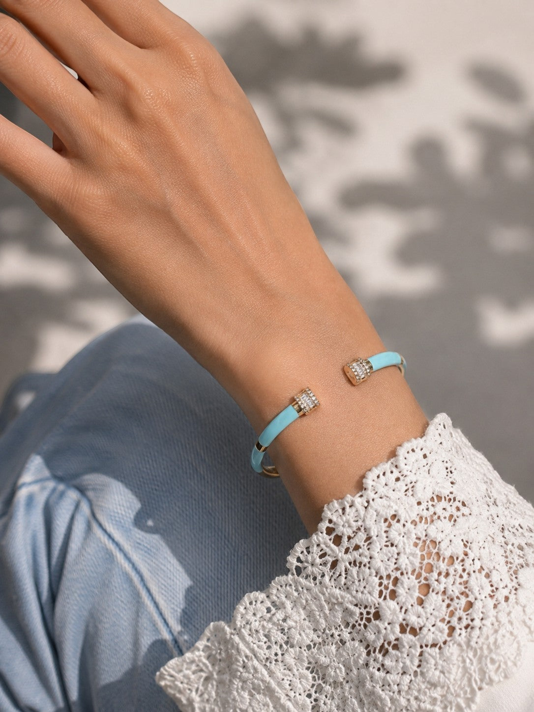 Daga-accessories blue enamel cuff bracelet with crystal accents worn on a woman's wrist with lace sleeve