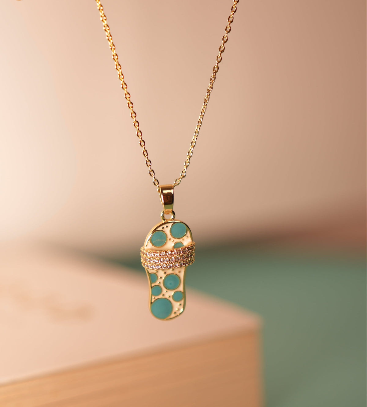 Daga-accessories gold chain necklace with a blue sandal pendant featuring sparkling crystal accents.