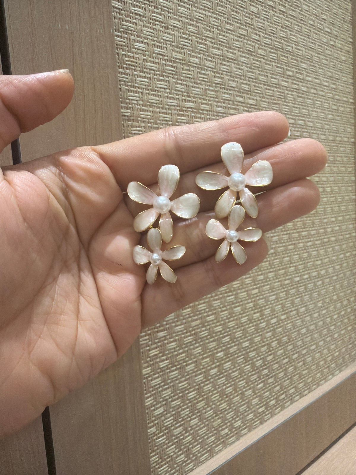 Daga-accessories Blush bloom drop earrings with pale ivory floral petals and a central pearl held in a hand