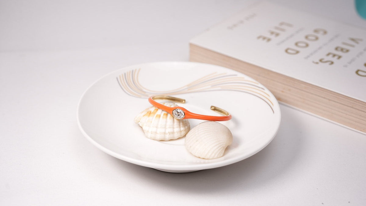 Daga-accessories coral crystal cuff bracelet resting on white seashells in a decorative dish