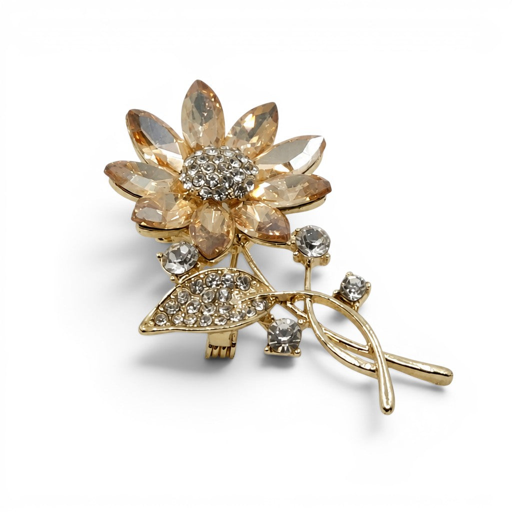 Daga-accessories crystal studded flower brooch with gold-tone metal, champagne petals, and clear sparkling accents.