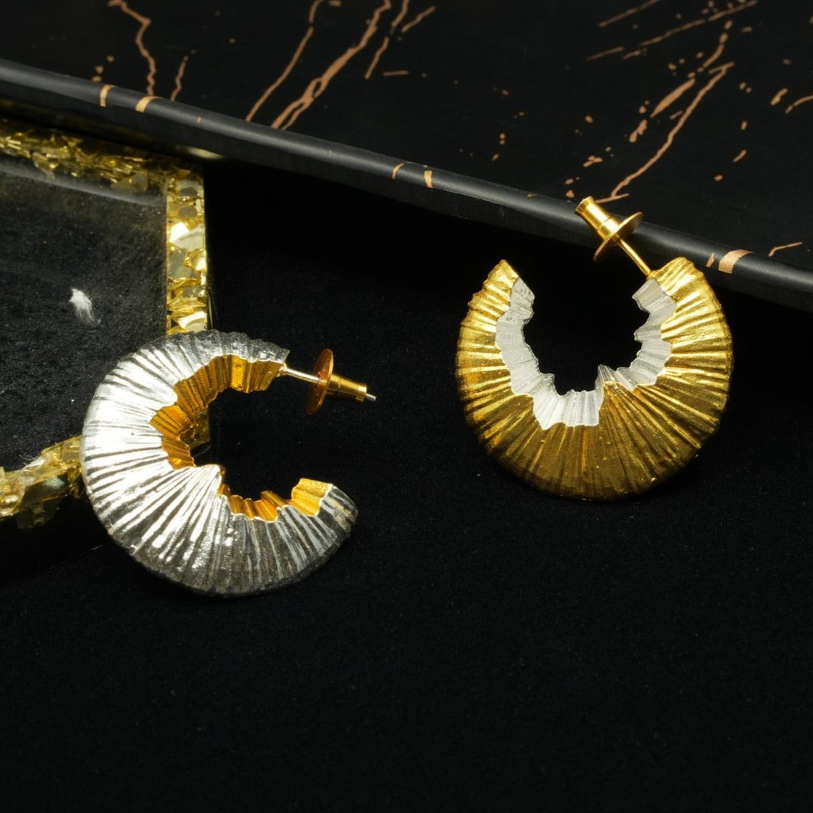 Daga-accessories The Dual Shaved Hoop earrings featuring a textured, semi-circular design in gold and silver tones.