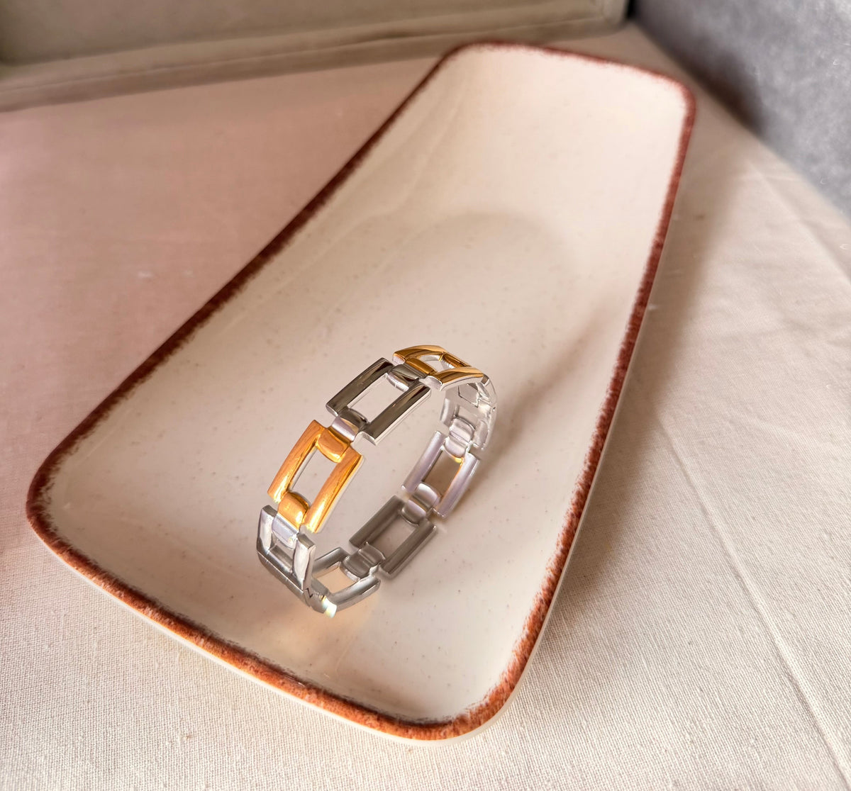 Daga-accessories Dual Armor Cuff featuring a structured, dual-tone gold and silver metal link design on a ceramic tray.