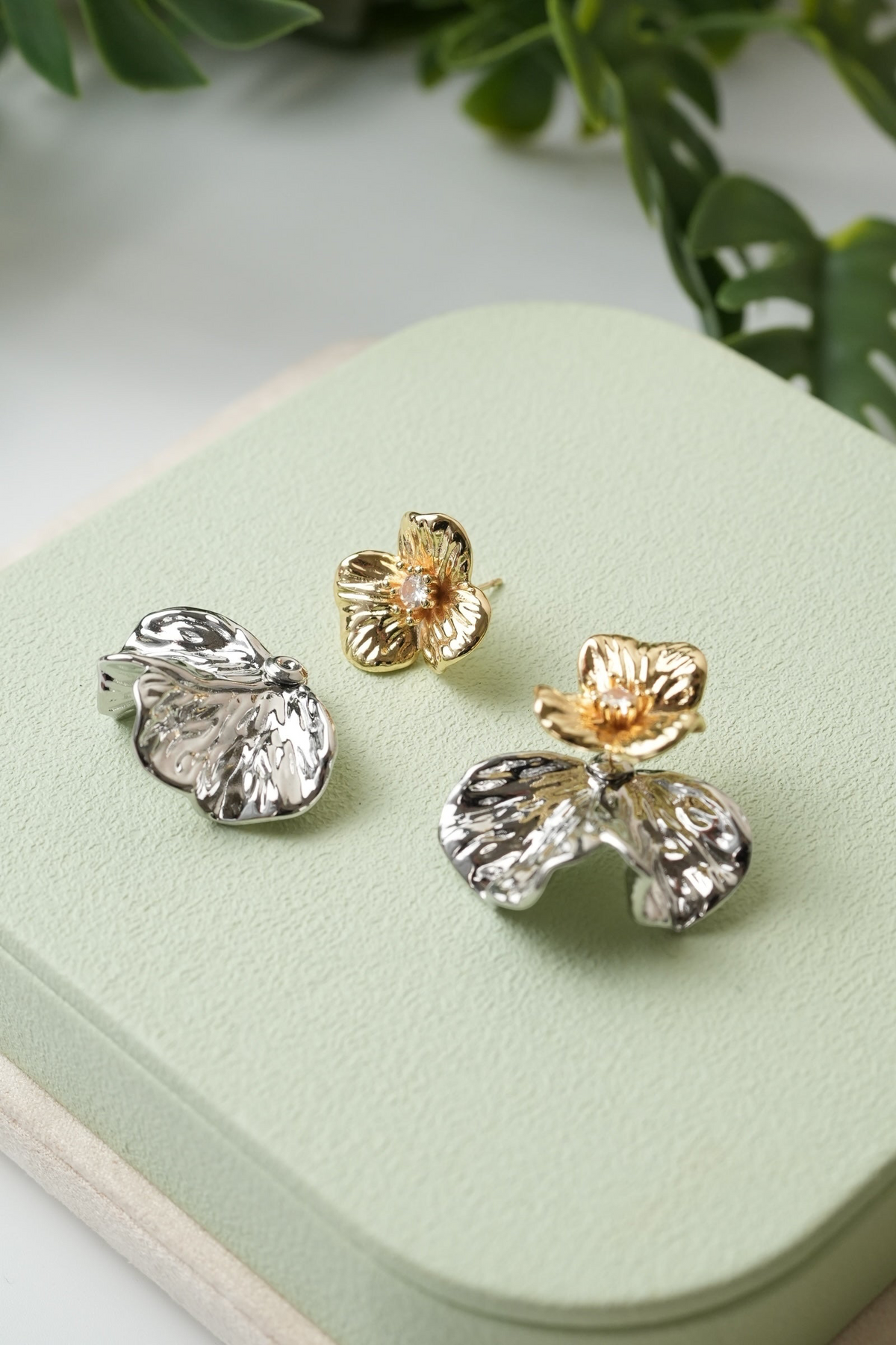 Daga-accessories dual-tone floral stud earrings with textured silver and gold petals and a central sparkling stone.