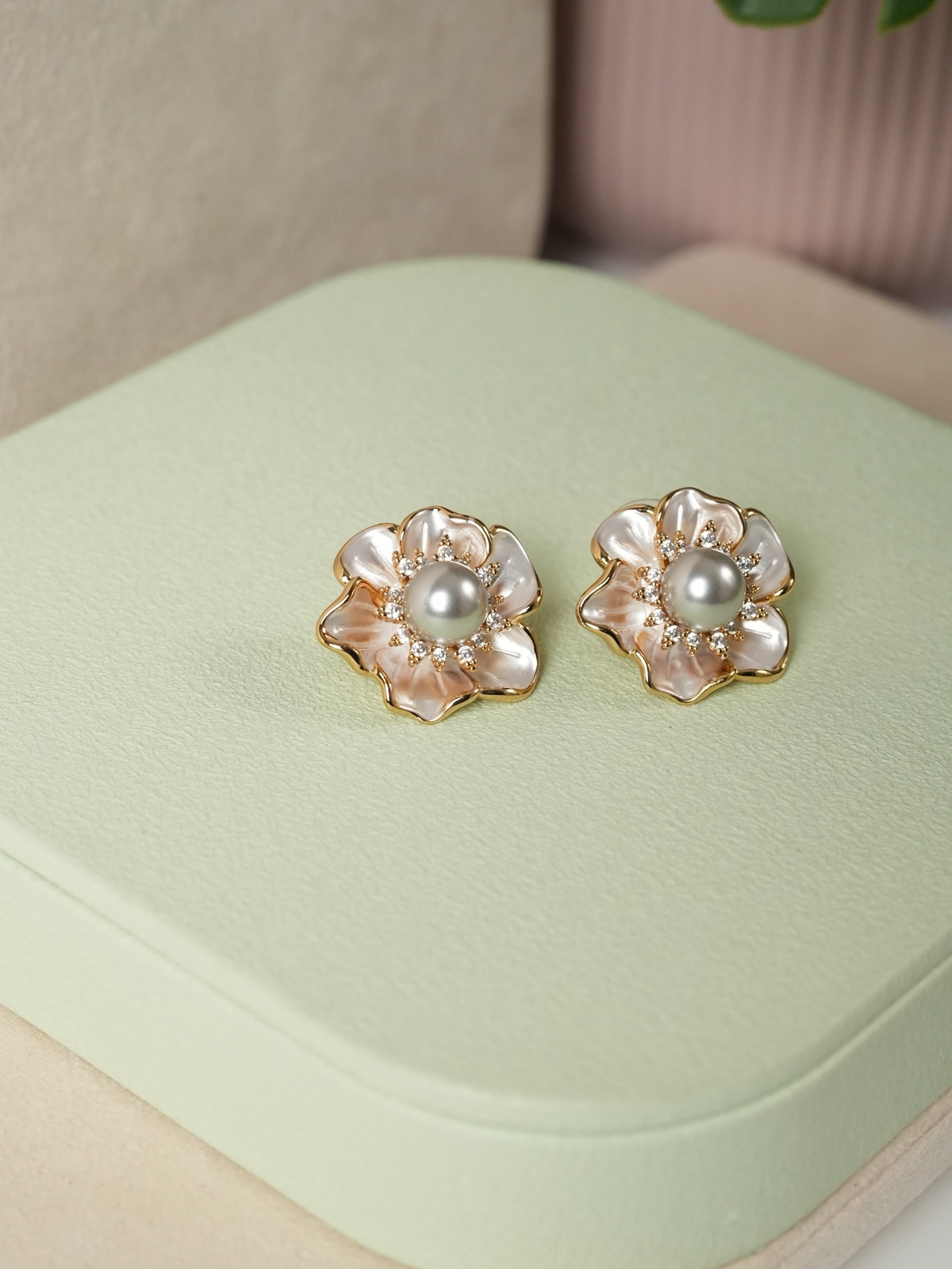 Daga-accessories floral stud earrings with iridescent petals, central pearl, and shimmering stones in gold-tone setting