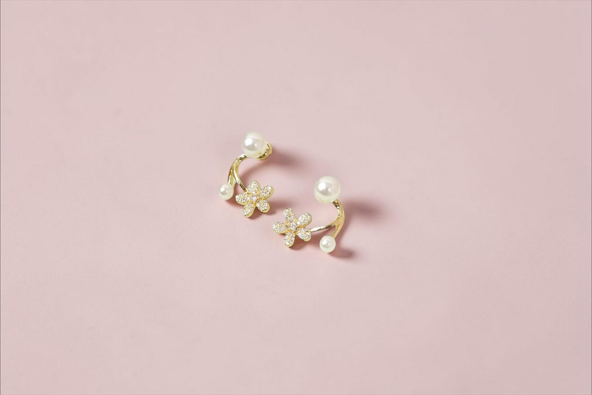 Daga-accessories floral stud earrings with cubic zirconia flowers and faux pearls on a gold-toned curved frame.