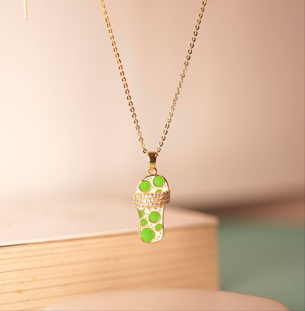Daga-accessories Glided Footprint Glow Mint necklace featuring a gold chain and a sandal-shaped pendant with mint spots