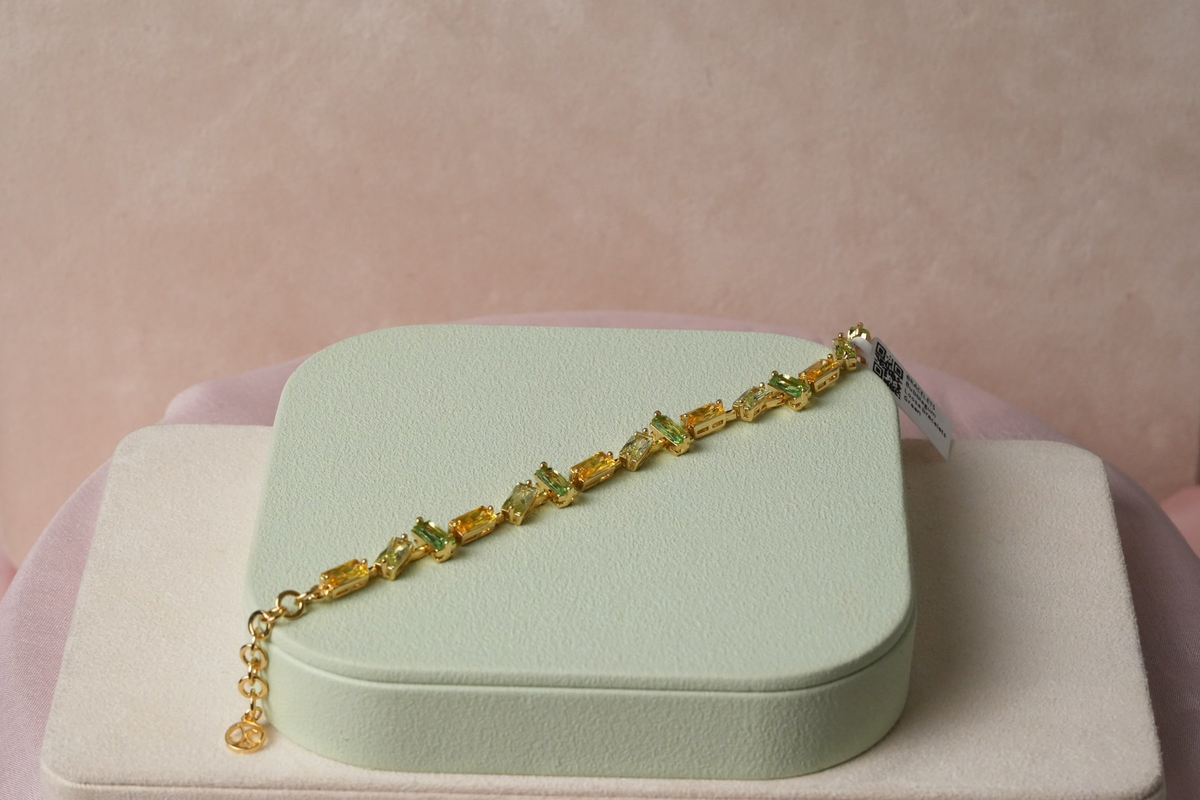 Daga-accessories gold-toned bracelet featuring rectangular baguette-cut green and yellow crystals on a delicate chain.