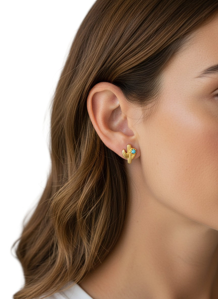 Daga-accessories gold-tone cactus stud earrings with a turquoise stone accent worn on a woman's ear