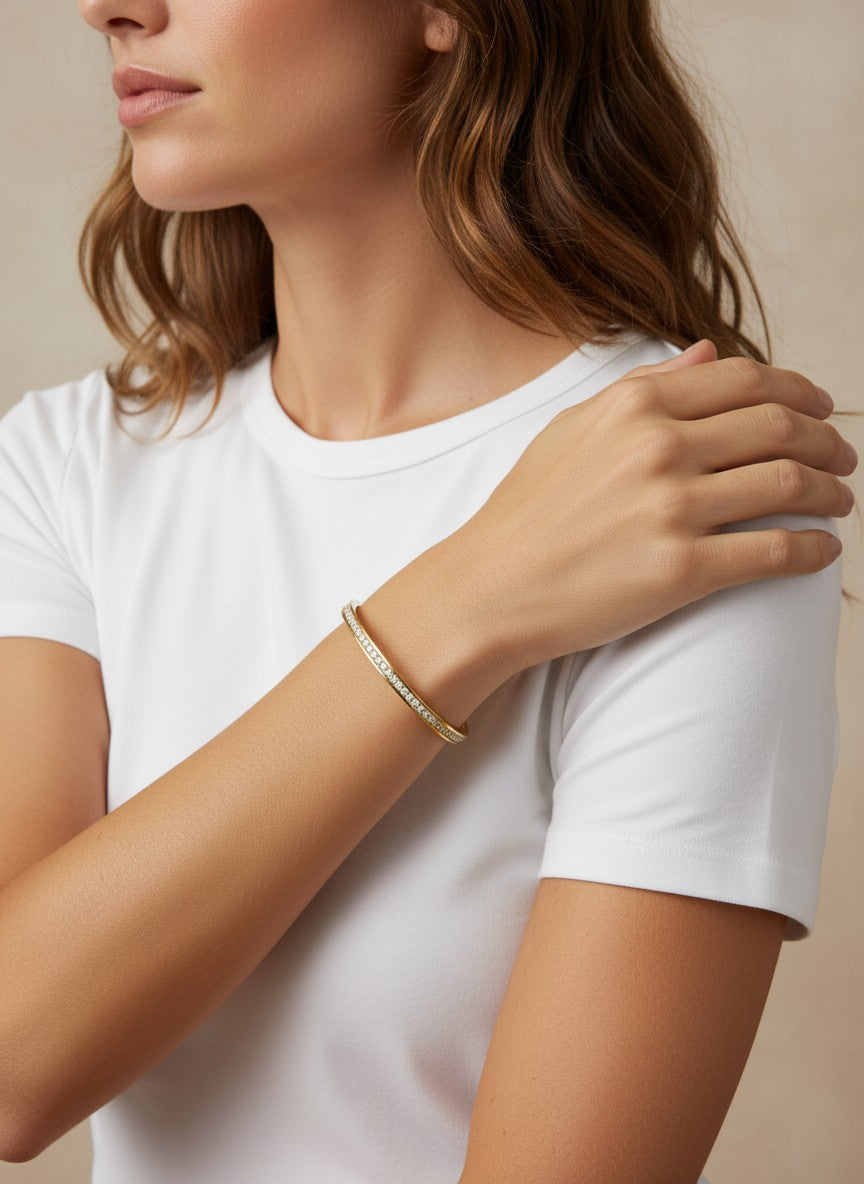Daga-accessories gold-toned bangle bracelet with clear crystal embellishments worn on a woman's wrist