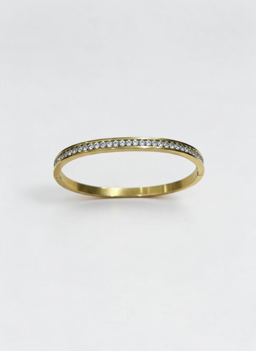 Daga-accessories gold-toned bangle bracelet featuring a row of shimmering cubic zirconia stones on a polished band.