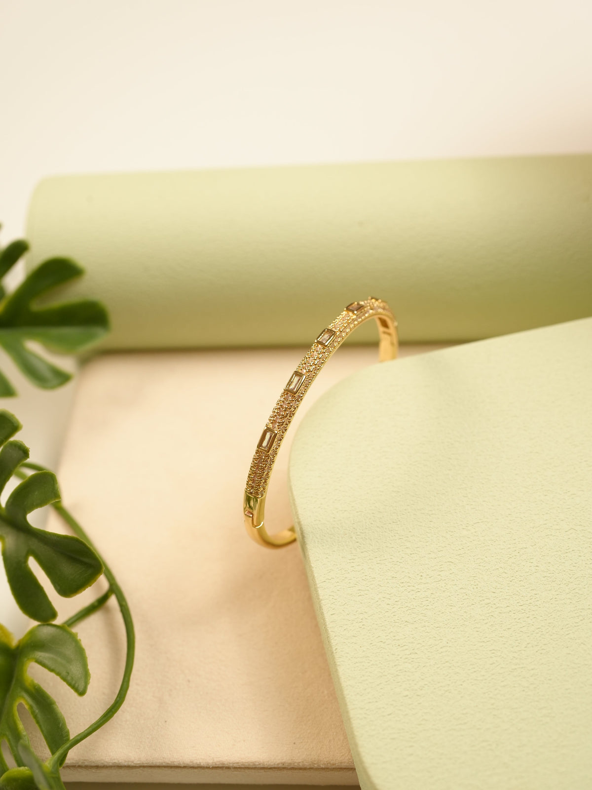 Daga-accessories gold Diamond Glow bracelet with studded crystal accents on a minimalist green and beige display