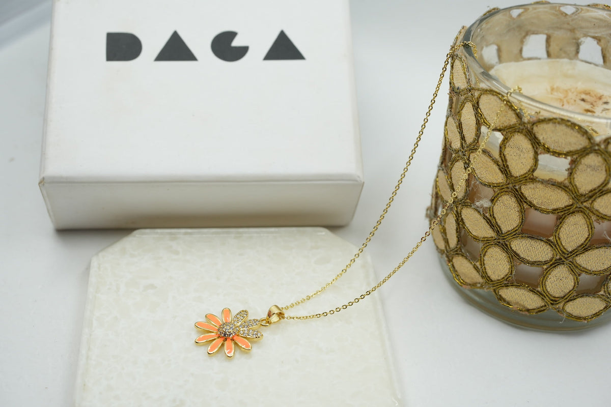 Daga-accessories gold stainless steel necklace featuring a dainty orange enamel flower pendant with crystal center.