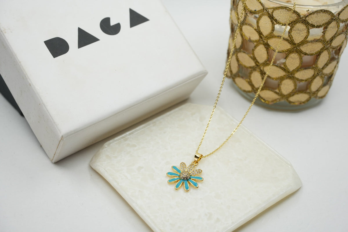 Daga-accessories gold stainless steel necklace featuring a blue enamel flower pendant with a sparkling crystal center.
