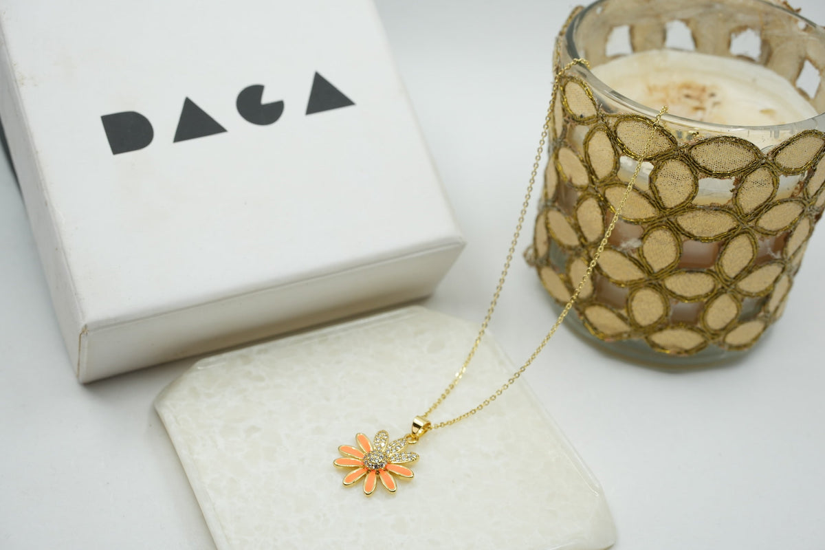 Daga-accessories gold stainless steel necklace featuring a dainty orange enamel flower pendant with crystal accents.