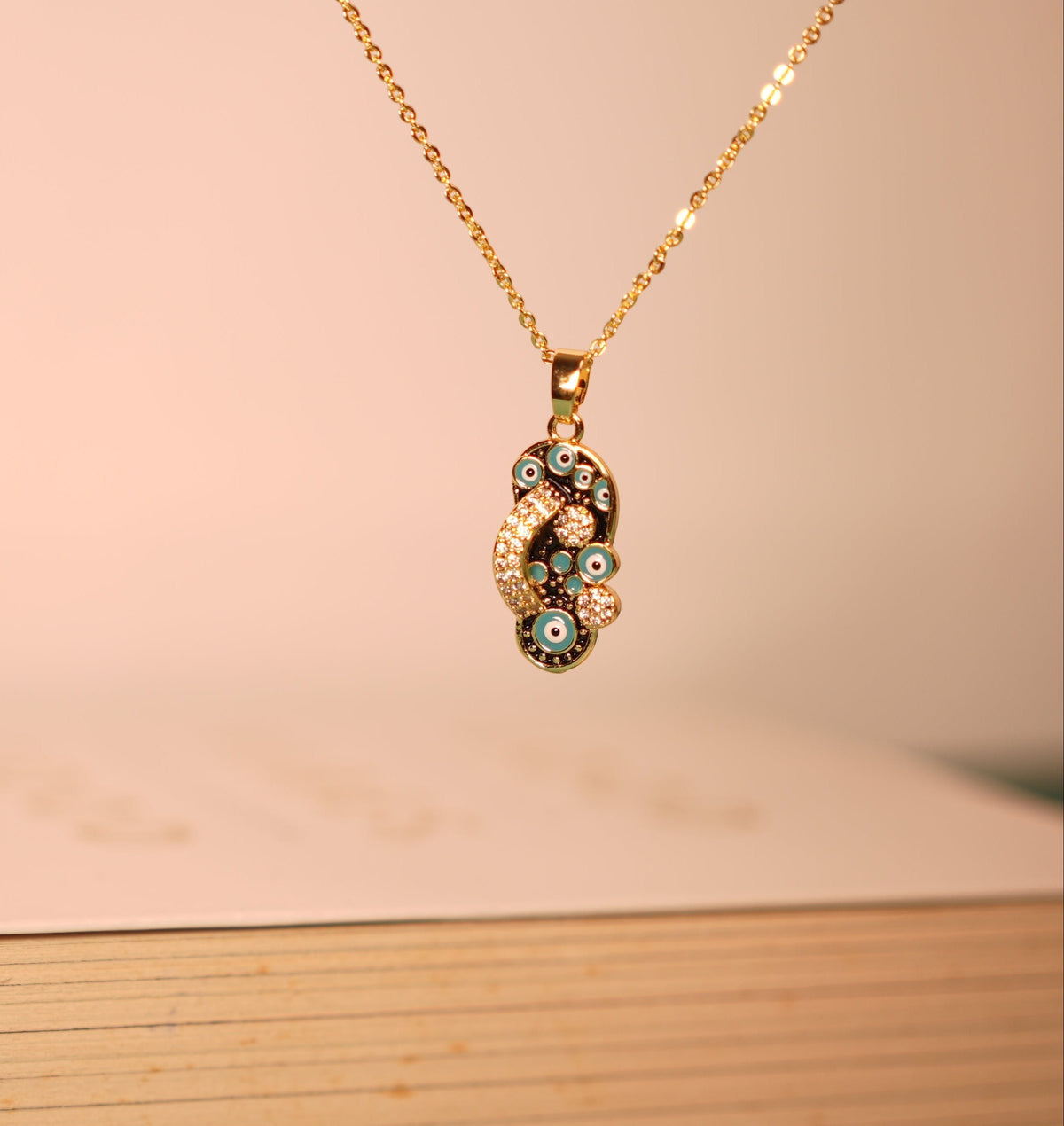 Daga-accessories gold chain necklace featuring a pendant with blue evil eye charms and sparkling crystal accents