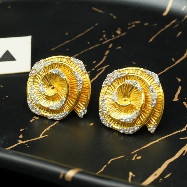 Daga-accessories floral stud earrings in brushed gold-tone metal with shimmering crystal accents on a black tray.