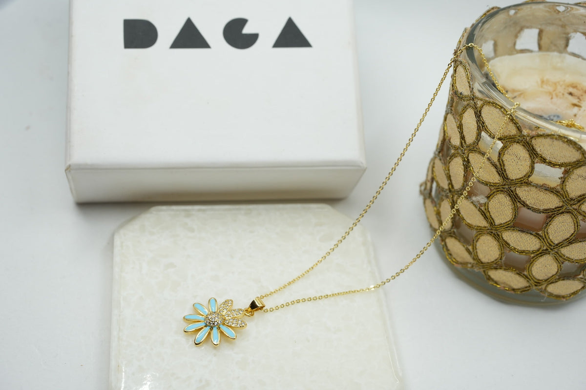 Daga-accessories gold stainless steel necklace featuring a dainty flower pendant with light blue enamel and crystals.