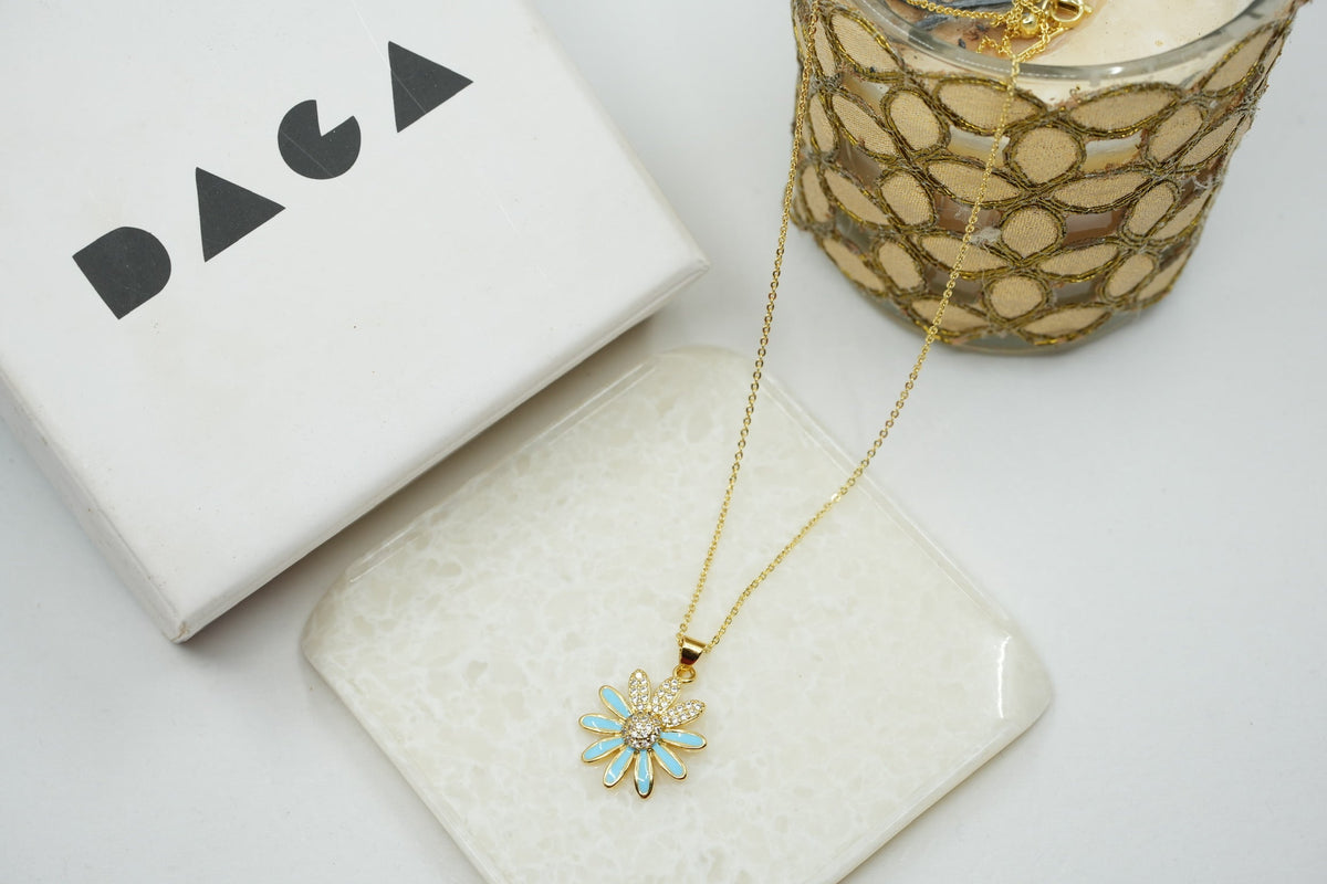 Daga-accessories gold stainless steel necklace featuring a dainty flower pendant with light blue enamel and crystals.