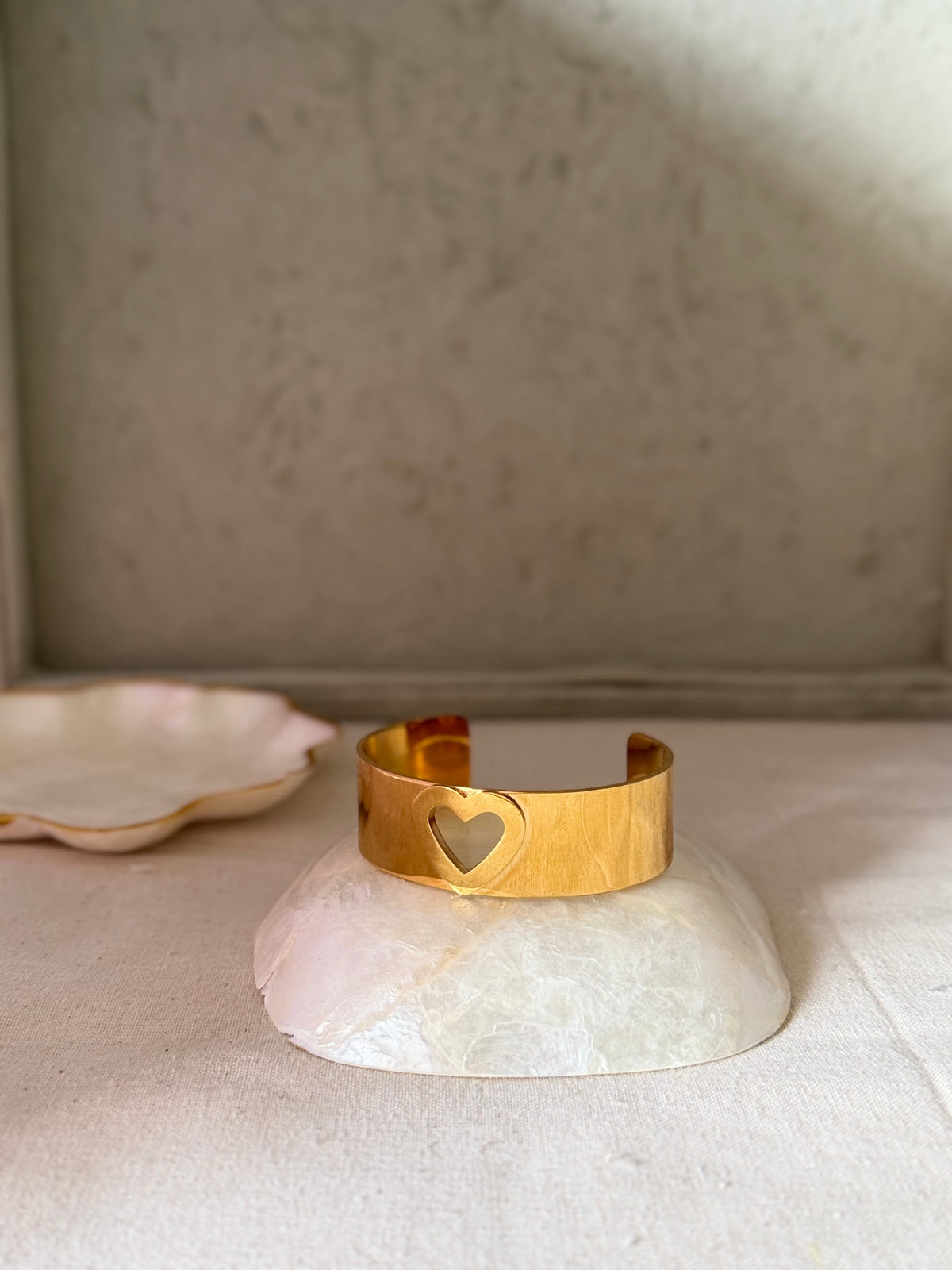 Daga-accessories gold cuff bracelet featuring a delicate heart-shaped cut-out design on a polished metal band.