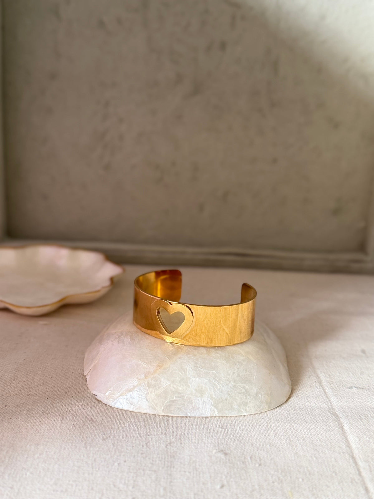 Daga-accessories golden cuff bracelet featuring a delicate heart-shaped cut-out design on a polished metal band.
