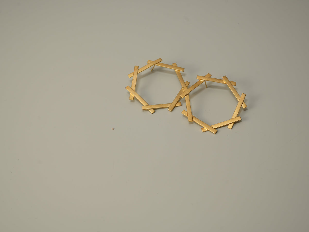 Daga-accessories gold stud earrings featuring a geometric hexagon frame made of thin metallic bars