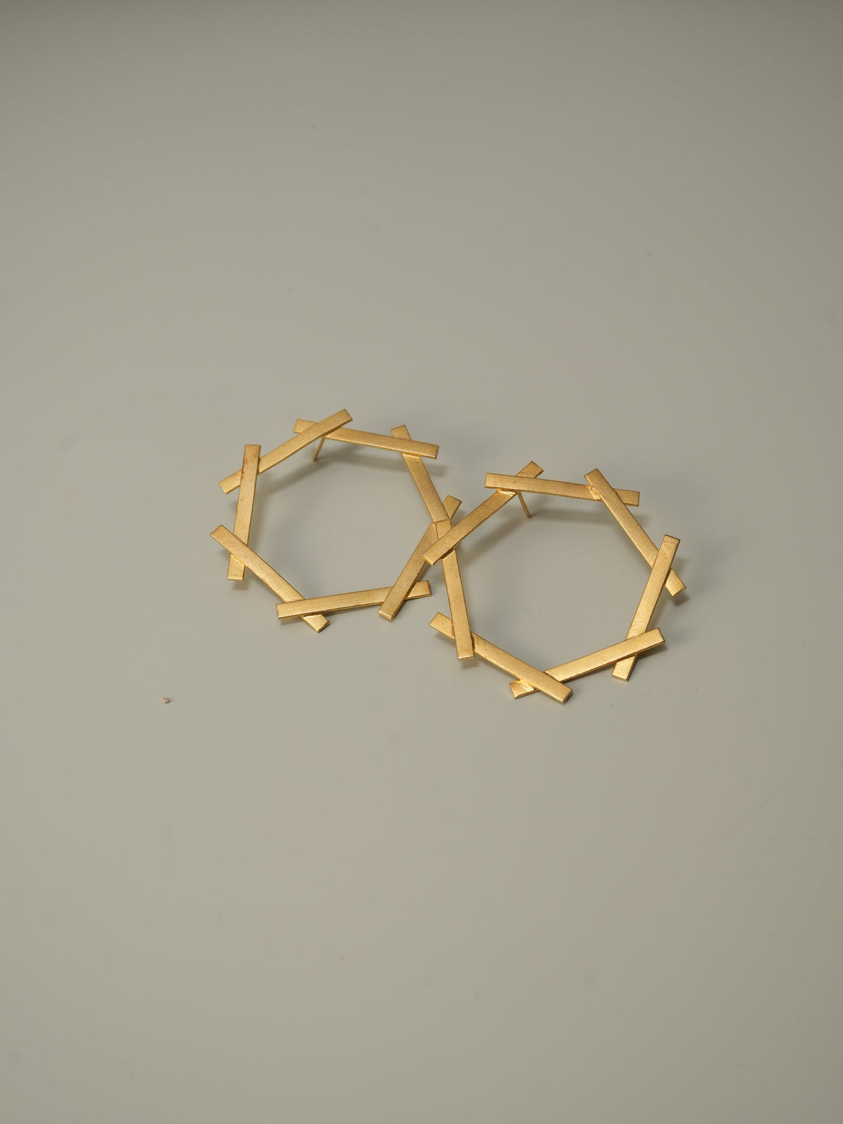 Daga-accessories gold hexagon stud earrings with a geometric bar design on a neutral background