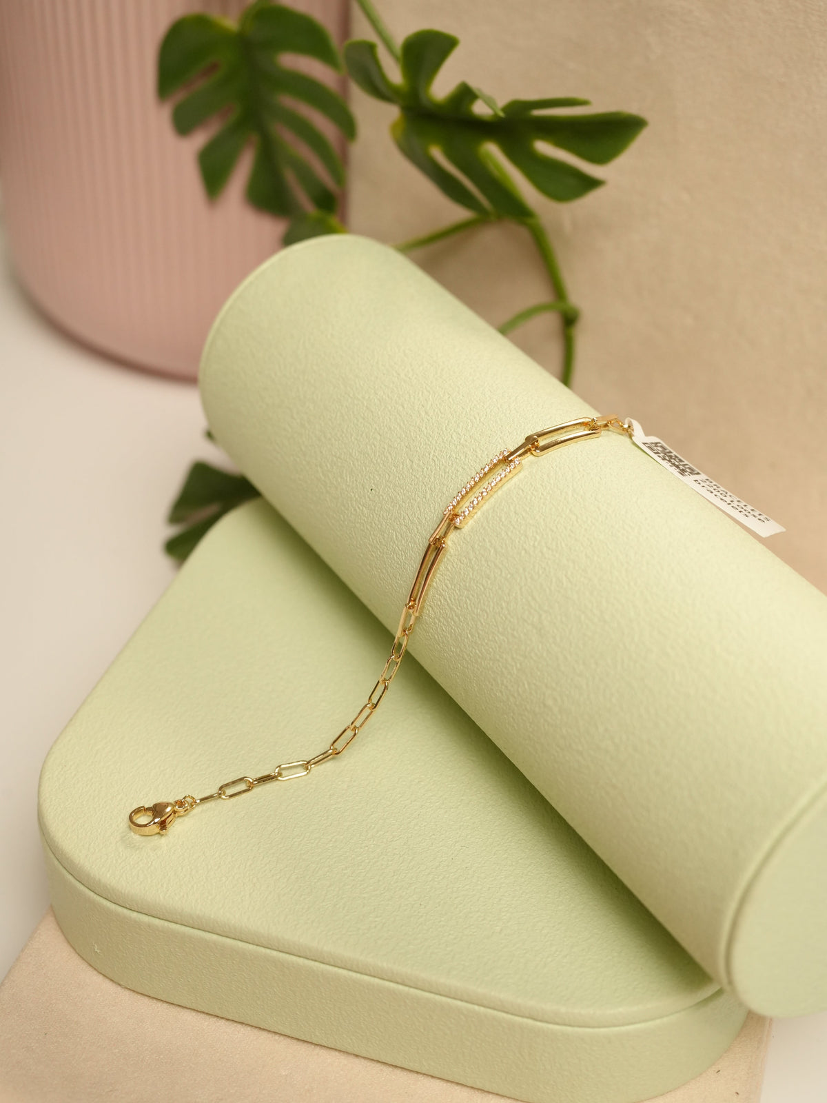 Daga-accessories gold link bracelet with delicate crystal-encrusted bar detail displayed on a light green stand