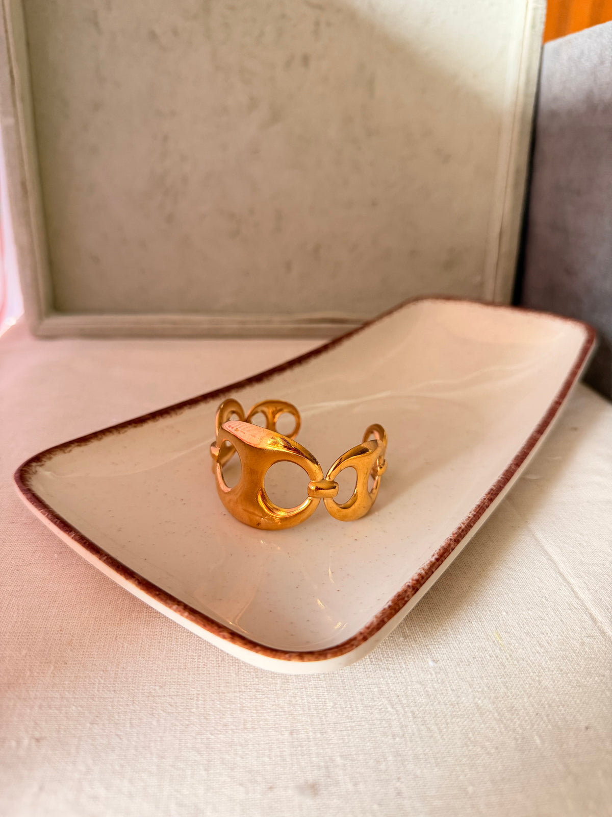 Daga-accessories Heritage Gold Link Cuff featuring polished interlocking gold links on a ceramic display tray.