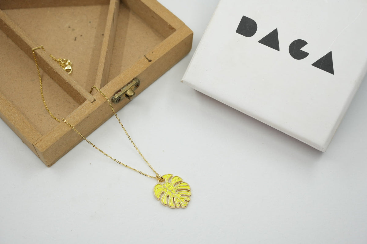 Daga-accessories gold chain necklace featuring a yellow monstera leaf pendant, displayed with a wooden box and gift box