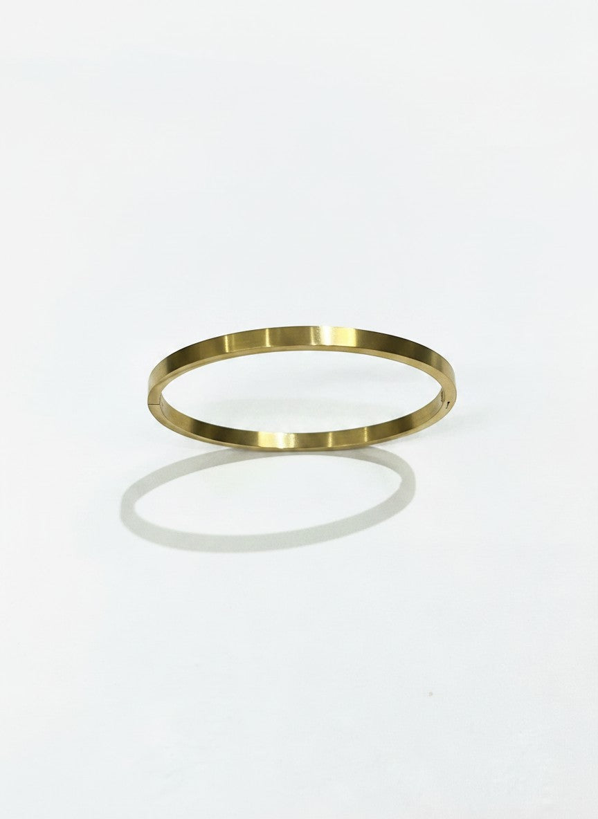 Daga-accessories minimalist gold-toned stainless steel bangle bracelet with a sleek polished finish on white background