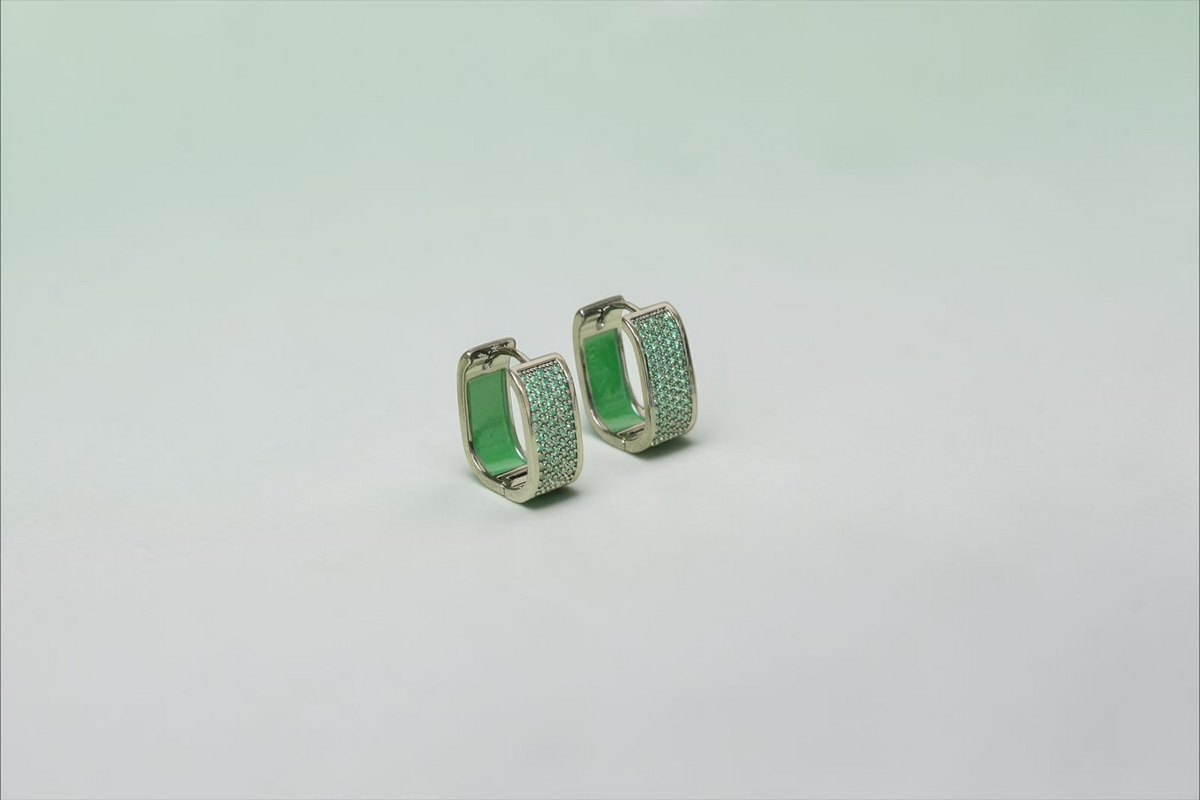 Daga-accessories rectangular hoop earrings in gunmetal with green micro-pave stones on a white display stand.