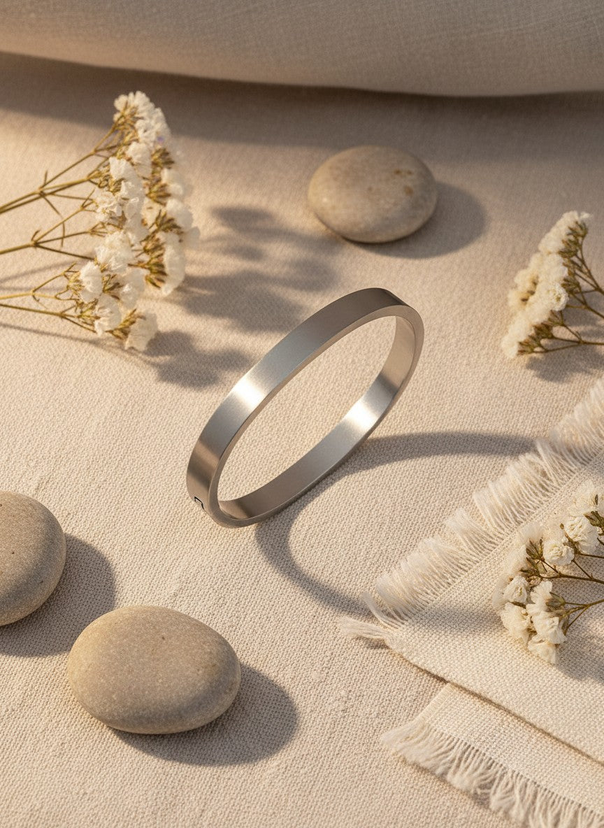 Daga-accessories minimalist silver-toned stainless steel bangle bracelet with a smooth polished finish on linen fabric