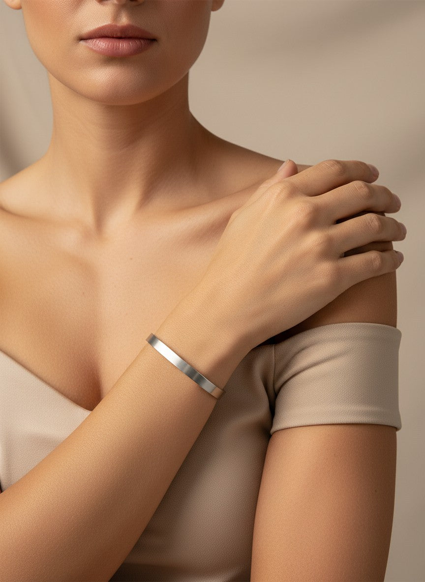 Daga-accessories minimalist stainless steel bangle bracelet with a polished metallic finish worn on a woman's wrist.