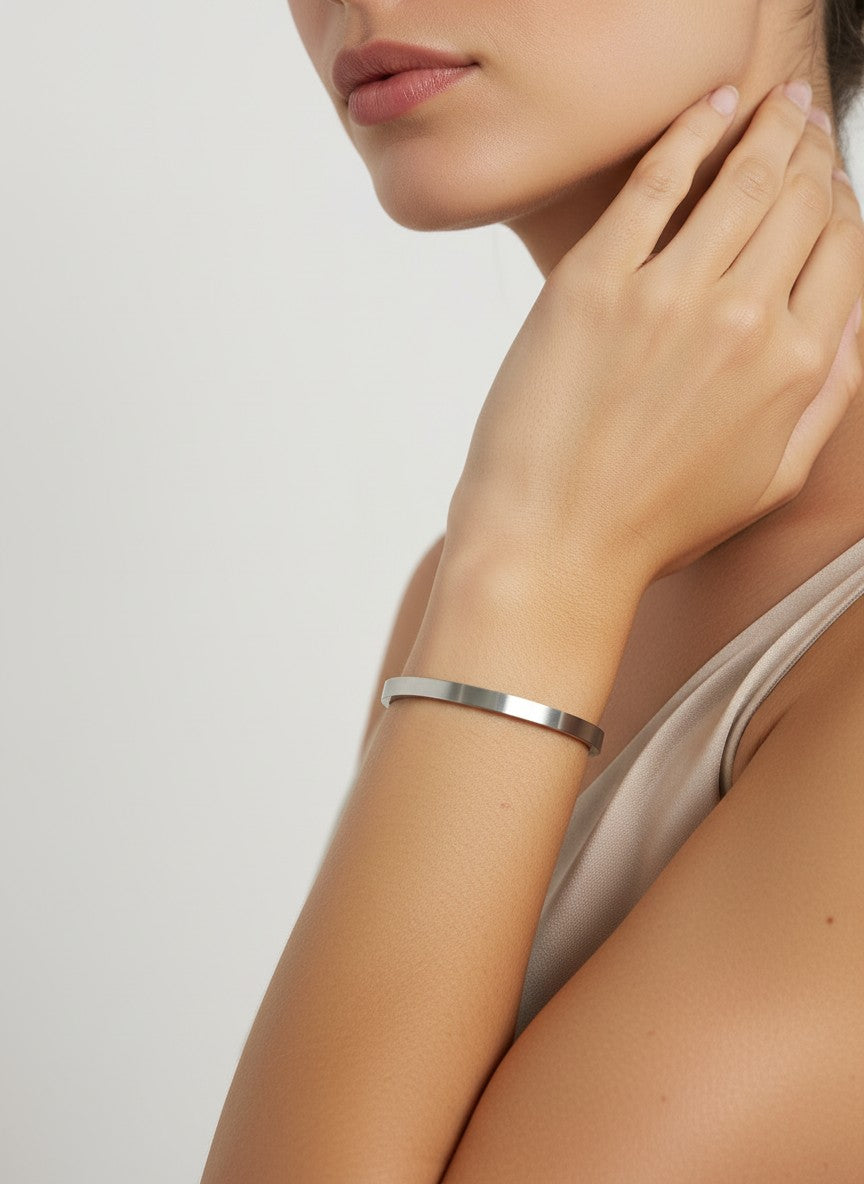 Daga-accessories minimalist stainless steel bangle bracelet with a polished silver finish worn on a woman's wrist.