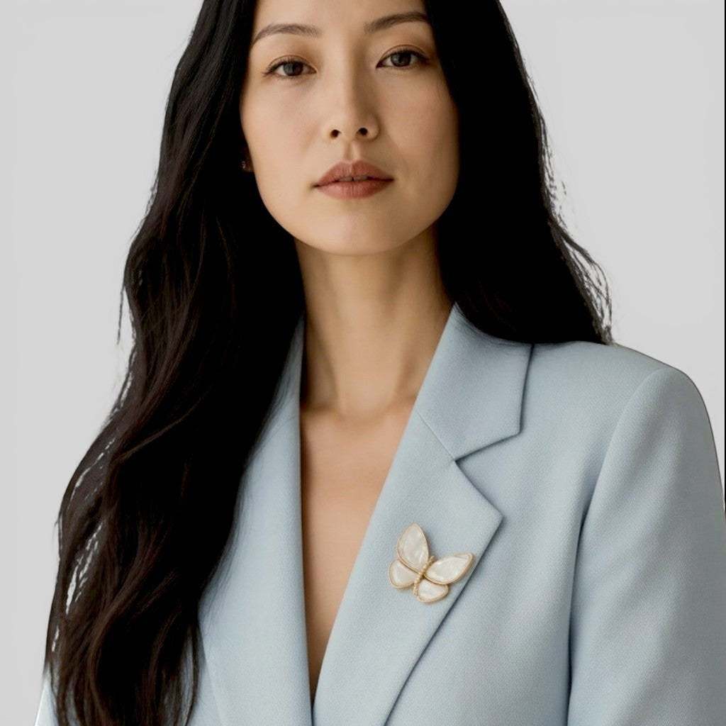 Daga-accessories MOP butterfly brooch with iridescent mother of pearl wings pinned to a light blue blazer