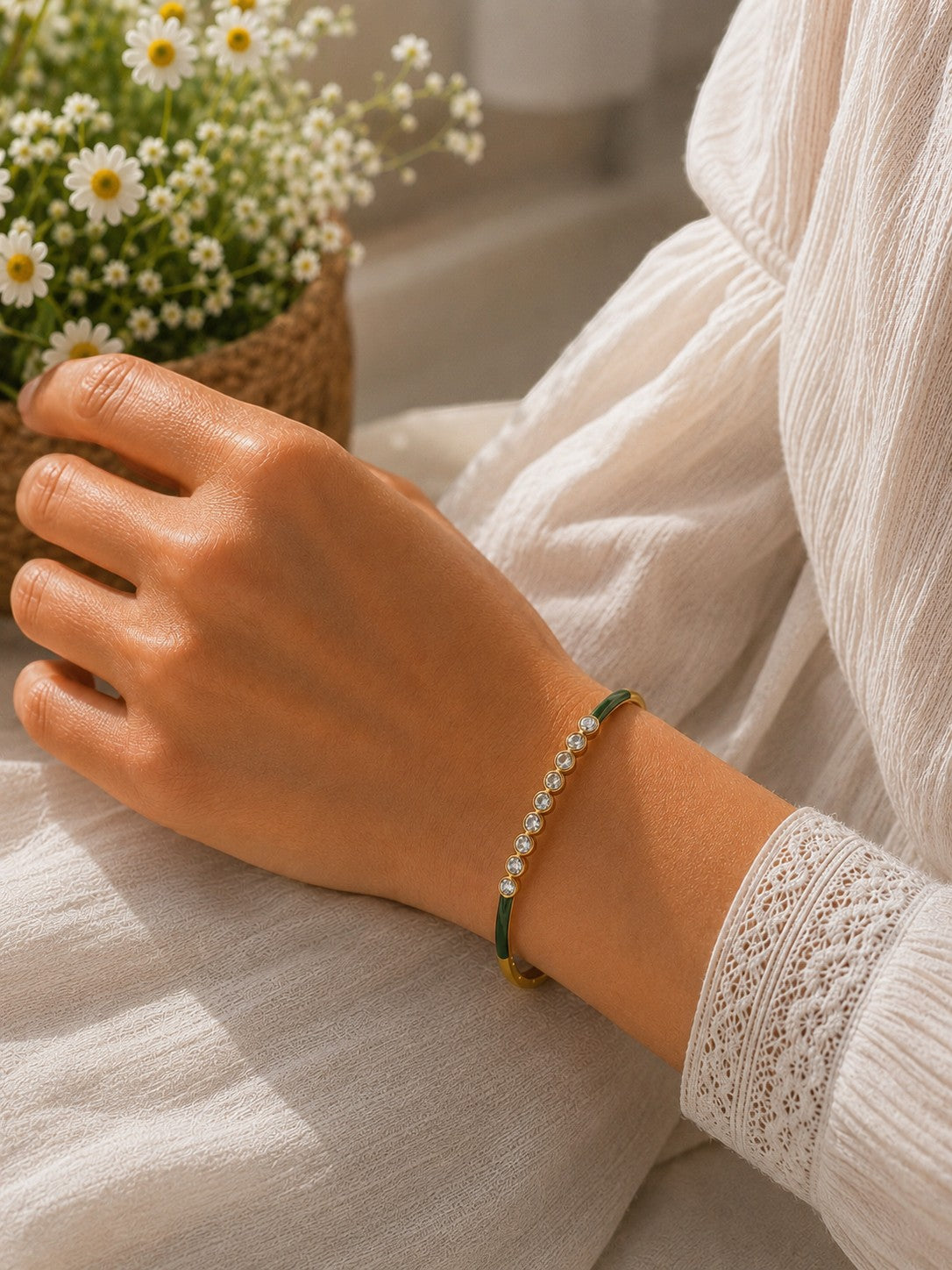 Daga-accessories olive green enamel bracelet with sparkling crystals worn on a woman's wrist in a bright setting.