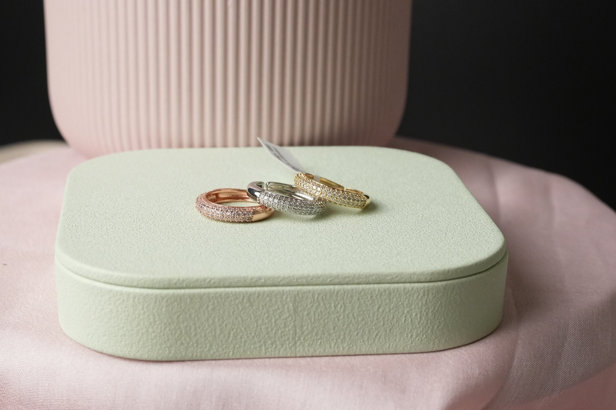 Daga-accessories pave-set band rings in rose gold, silver, and gold tones displayed on a soft green jewellery stand.