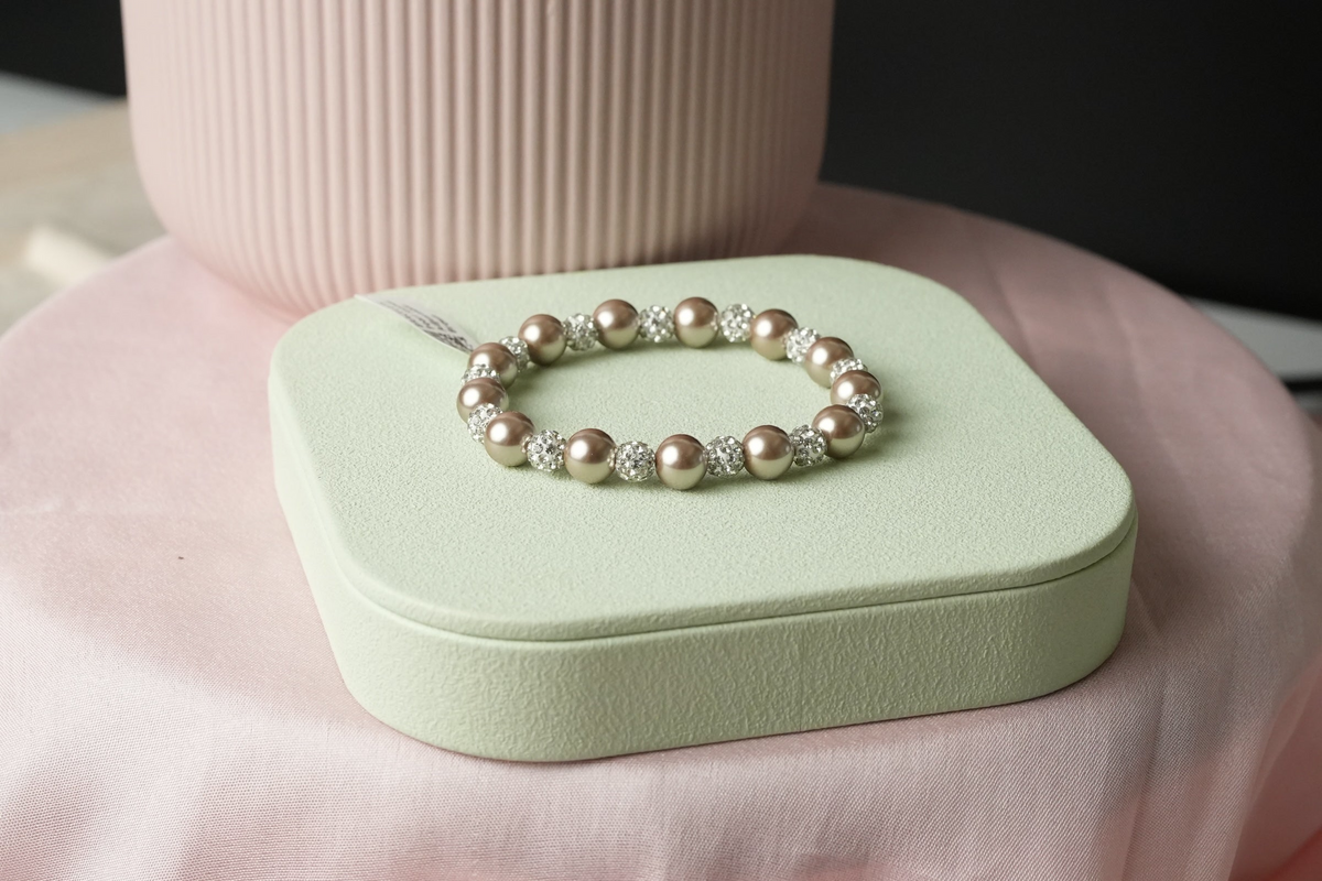 Daga-accessories champagne faux pearl and crystal beaded stretch bracelet on a soft green display stand