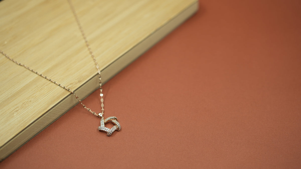 Daga-accessories Pentra gold necklace with a geometric studded pendant on a sleek chain against a wooden background