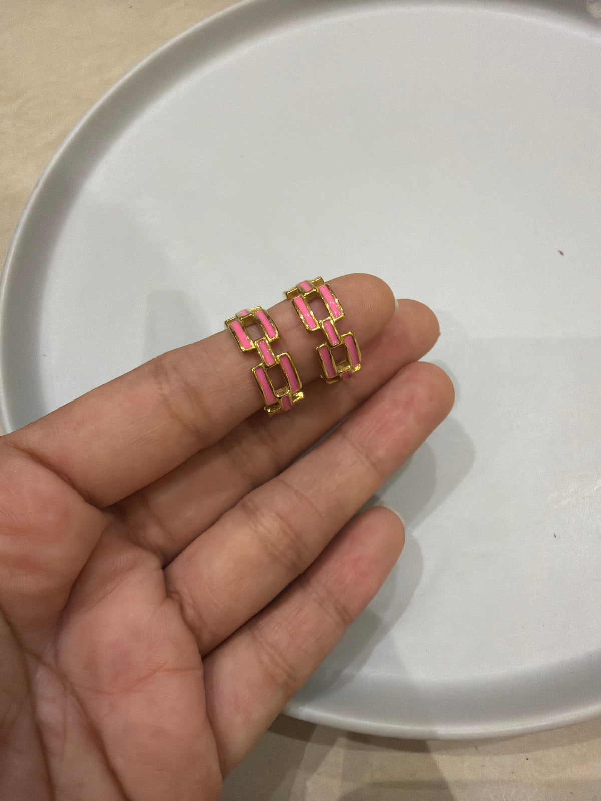 Daga-accessories gold hoop earrings featuring a pink enamel chain-link design held on fingers