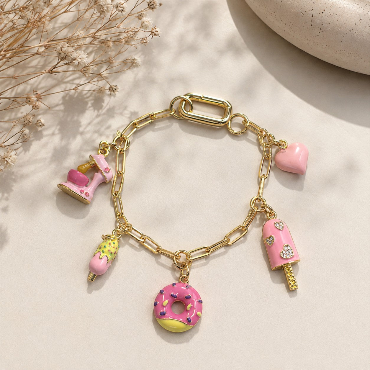 Daga-accessories gold-tone chain bracelet featuring pink enamel charms including a donut, popsicle, and heart.