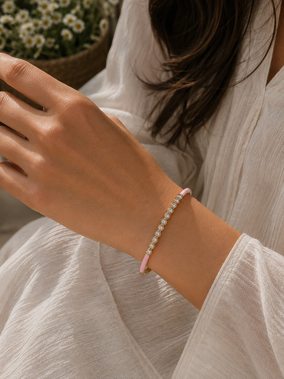 Daga-accessories pink enamel bracelet with sparkling crystal accents worn on a woman's wrist in a casual setting.