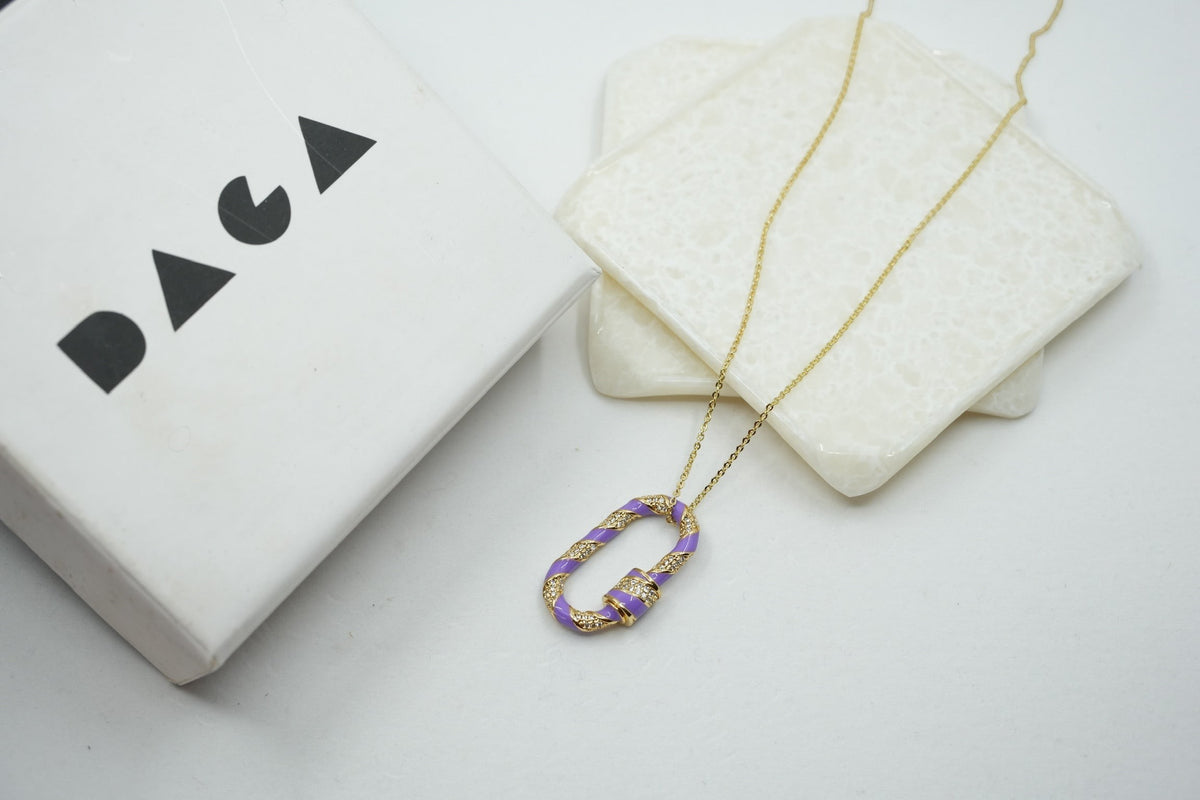 Daga-accessories paper link necklace with a purple enamel and gold-tone chain pendant on a white display surface.