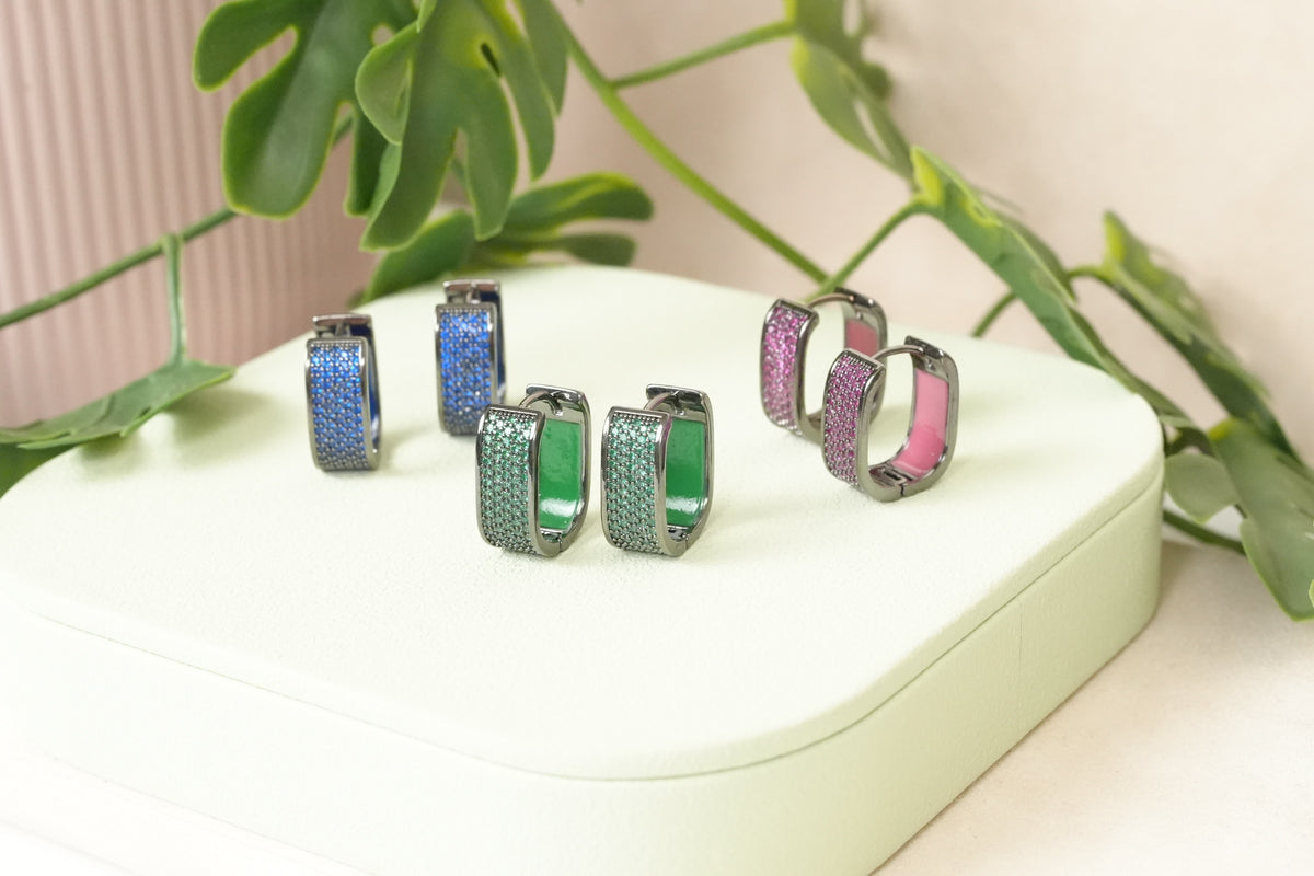 Daga-accessories rectangular hoop earrings with pave-set blue, green, and pink crystals on dark metallic frames.